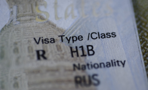 Fragment of H1B visa (for specialty workers) stamp in passport, blurred april calendar on background. H1B visa program deadline concept. Close up view.
